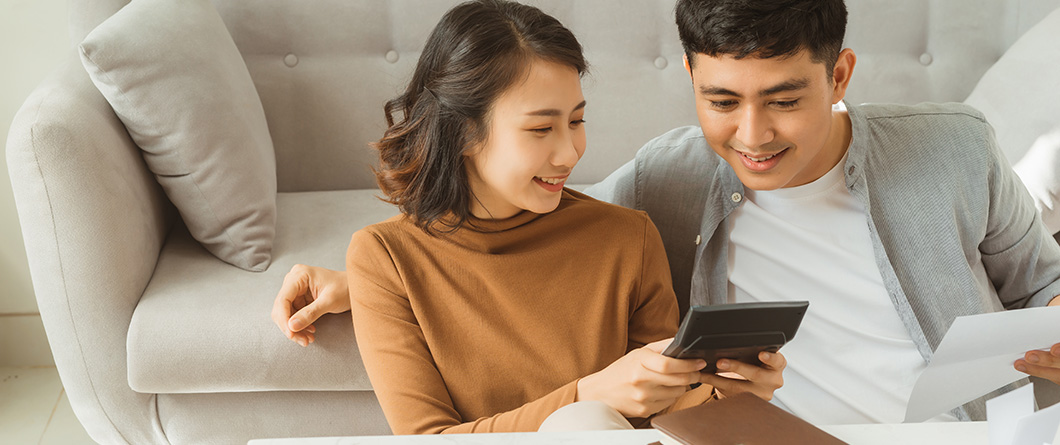 What Are Members Actually Doing Withshutterstock1650396691 | Evok Advertising Couple sitting on a beige sofa smiling as they look at a tablet together and review papers
