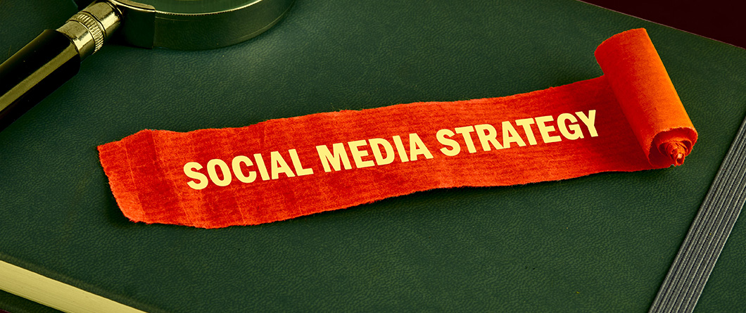 restaurant social media marketingshutterstock2532453089 | Evok Advertising Red torn ribbon reading 'SOCIAL MEDIA STRATEGY' on a green desk, with a magnifying glass nearby.