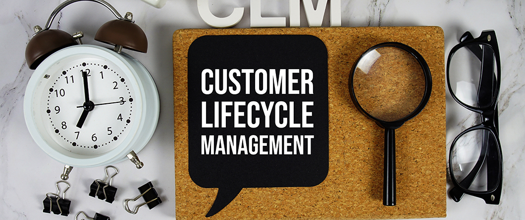 Lifecycle Marketing | Evok Advertising Clock magnifying glass glasses and binder clips surround a corkboard with a speech bubble reading'Customer Lifecycle Management'—illustrating business process focus.
