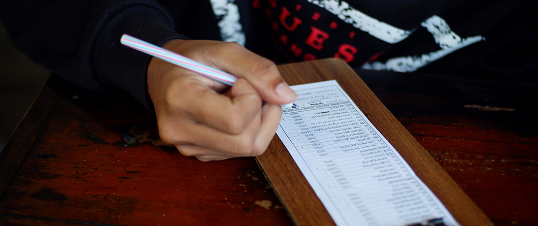 Building Your Restaurant Customer Database | Evok Advertising Persons hand writes on a long printed form with a striped pencil on a wooden table surface