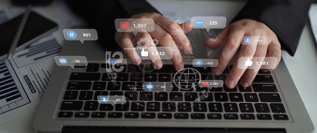 Measuring Healthcare Social Media Performanc | Evok Advertising Hands typing on a laptop with floating social icons and engagement numbers hovering above the keyboard