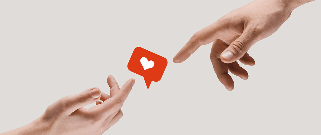 Platform Selection for Healthcare | Evok Advertising Two hands reach toward a red heart in a chat bubble icon floating between them symbolizing connection or appreciation in social media