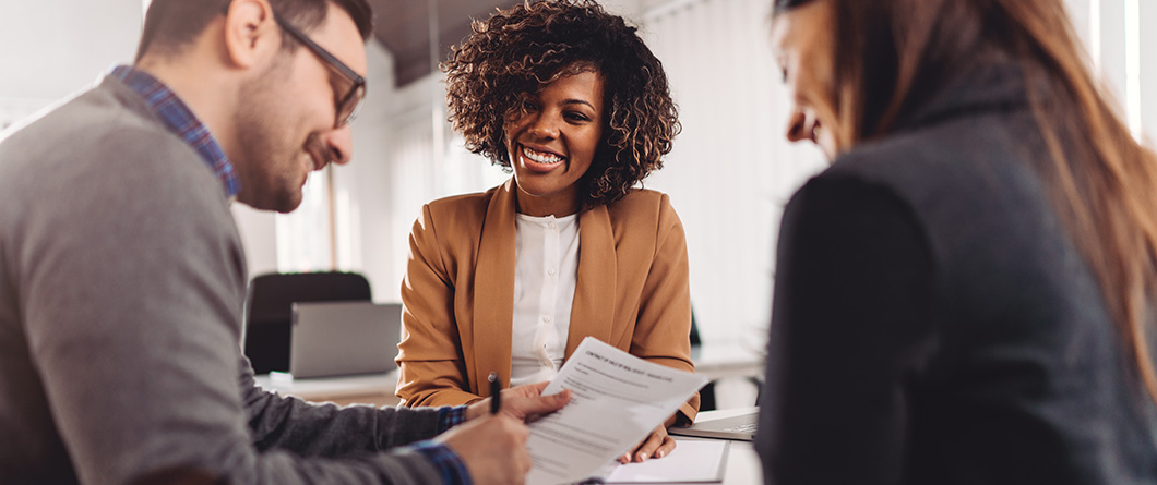 RateLed Versus RelationshipLed Deposit | Evok Advertising Three coworkers sit at a table reviewing a document and smiling at the discussion