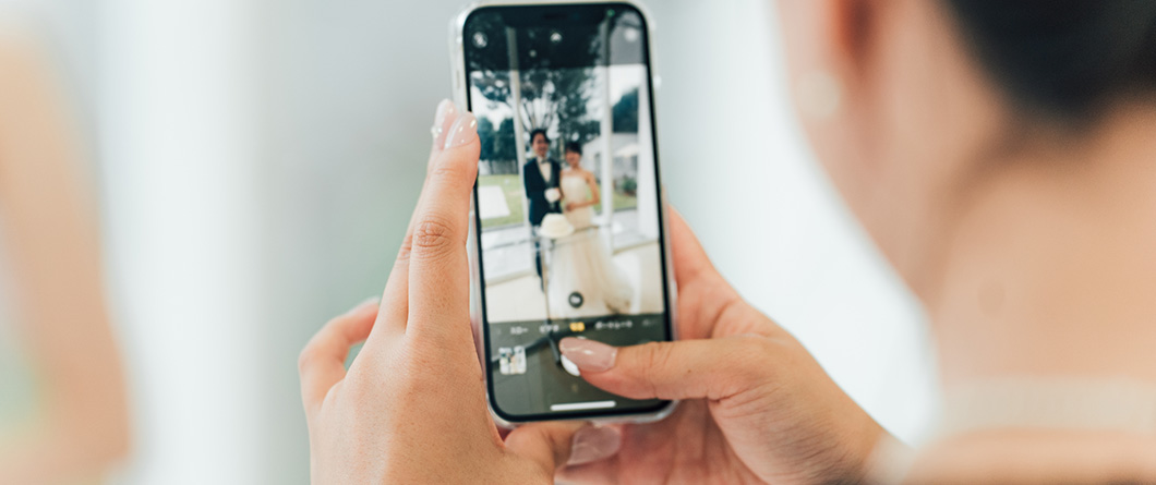 SmartphoneFirst Production | Evok Advertising Person holds a smartphone and captures a bride and groom posing outdoors